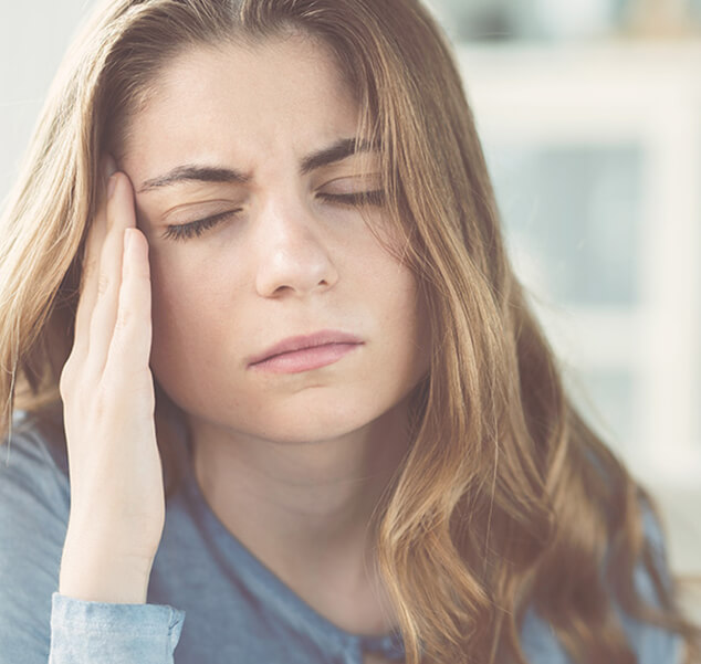 woman holding the side of her head in pain