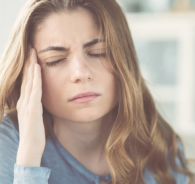 woman holding the side of her head in pain