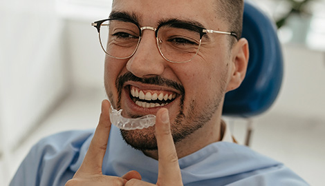 dental patient inserting a clear aligner onto his teeth